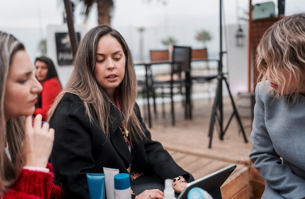 Three women talking or discussing sitting in front of a laptop outdoors