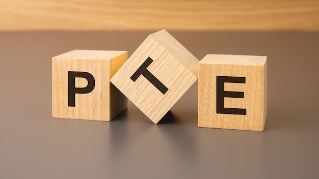 three wooden blocks on a brown background with the abbreviation PTE Pearson Tests of English