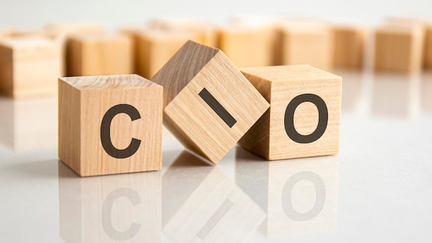 Three wooden blocks with the letters CIO on the bright surface of a gray table. the inscription on the cubes is reflected from the surface of the table. cio - chief information investment officer