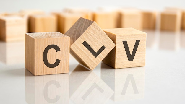 Three wooden blocks with the letters CLV on the bright surface of a gray table, business concept