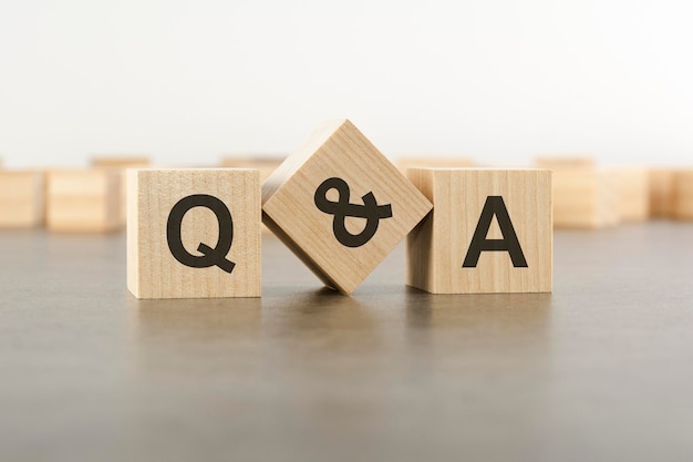 Three wooden blocks with letters Q and A with focus to the single cube in the foreground in a conceptual image on grey background