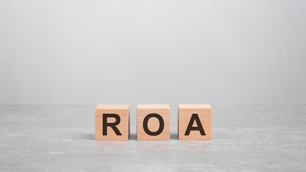 Three wooden blocks with the letters ROA on the bright gray table business concept ROA  short for Return On Assets