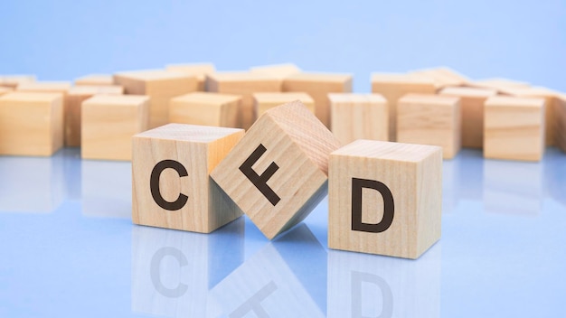 Three wooden cubes with the letters CFD on the bright surface of a pale lilac table the inscription on the cubes is reflected from the surface of the table business concept