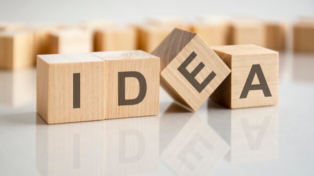 Three wooden cubes with the letters idea on the bright surface of a gray table. the inscription on the cubes is reflected from the surface of the table. business concept.