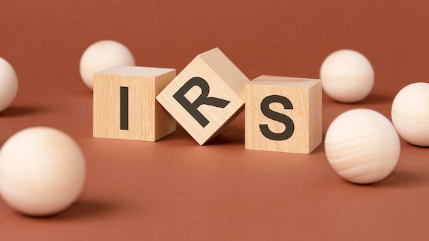 Three wooden cubes with the letters IRS on the bright surface of a brown table IRS short for Internal Revenue Service