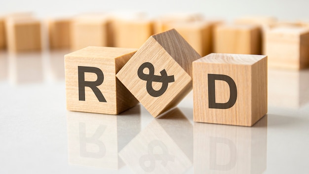 Three wooden cubes with the letters R and D on the bright surface of a gray table. the inscription on the cubes is reflected from the surface of the table. business concept. research and development