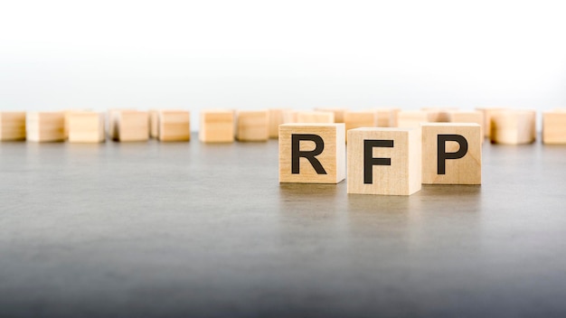 Three wooden cubes with the letters RFP on the bright surface of a gray table