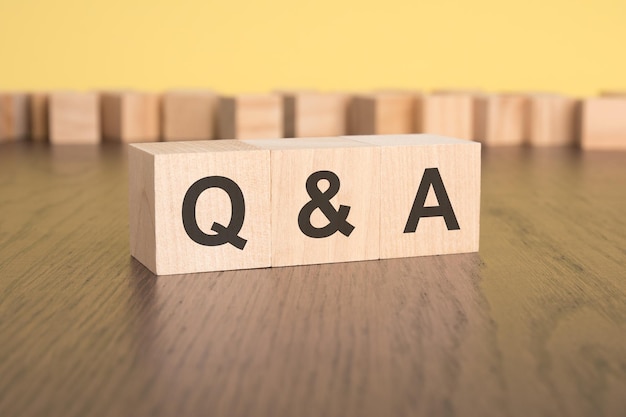 Three wooden cubes on a yellow background with the abbreviation q and a question and answer