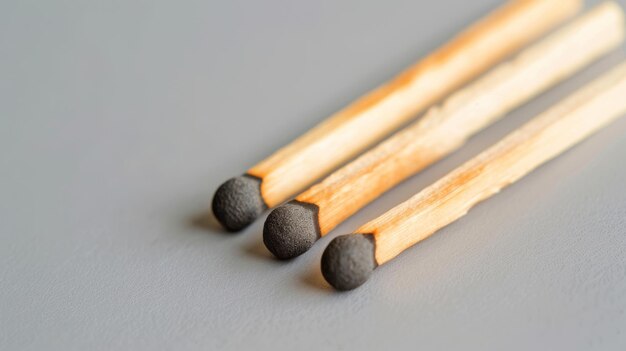 Photo three wooden matches their heads intact and unburnt positioned diagonally on a smooth grey surface