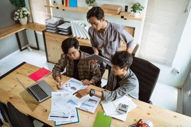 Three young asian businessman chatting about their product