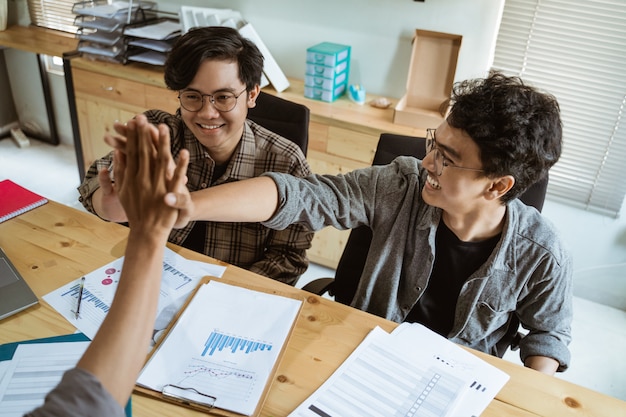 Three young Asian entrepreneur work together in agreement at planning with unite gesture