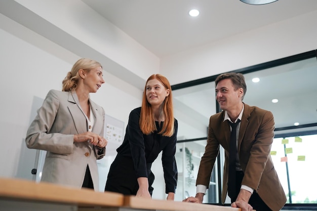 Three young business professionals standing together and discussing over business report