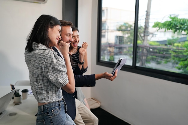 Three young business professionals standing together and discussing over business report