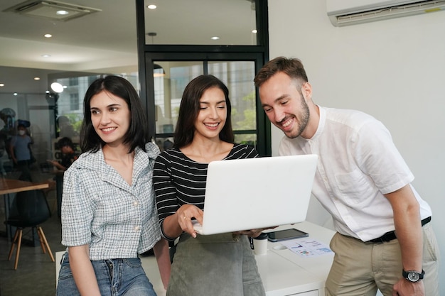 Three young business professionals standing together and discussing over business report