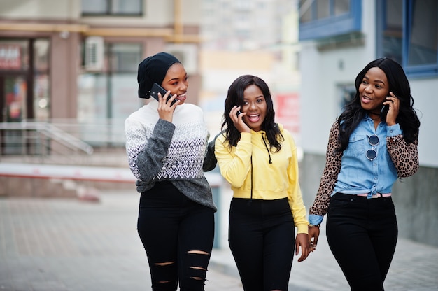 Three young college african american woman friends with mobile phones.