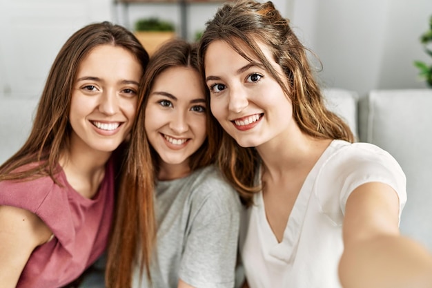 Three young hispanic woman smiling happy and make selfie by the smartphone sitting on the sofa at home.