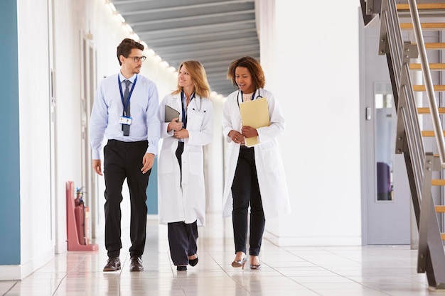 Three young male and female doctors walking in hospital