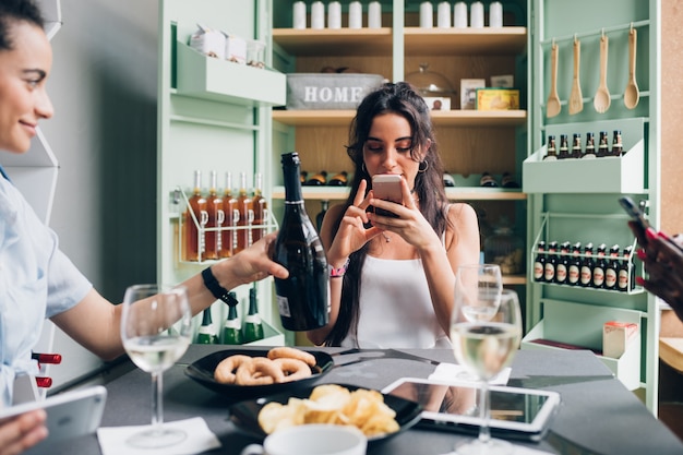 Three young multiracial women having aperitif in modern pub