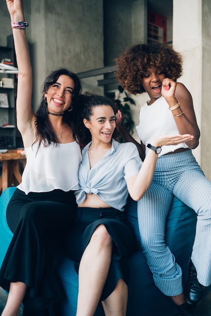 Three young multiracial women having fun and posing together in modern loft