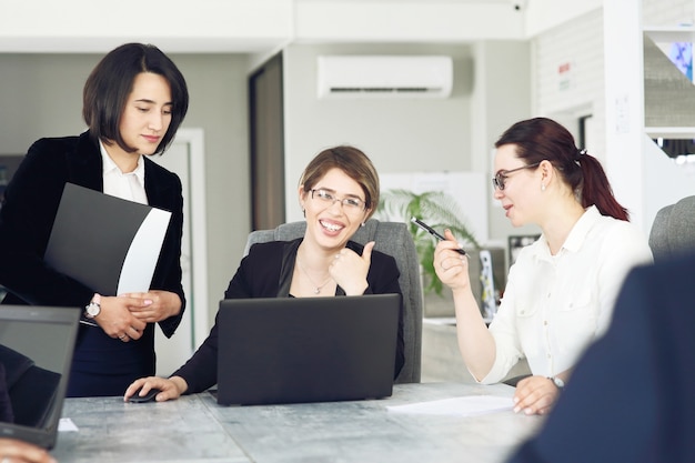 Three young successful business women in the office together happily working on a project