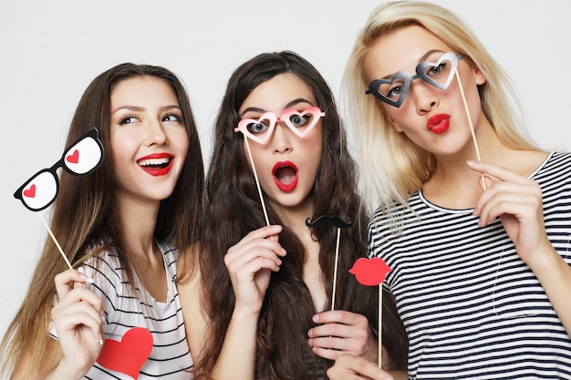 Three young women holding paper party sticks