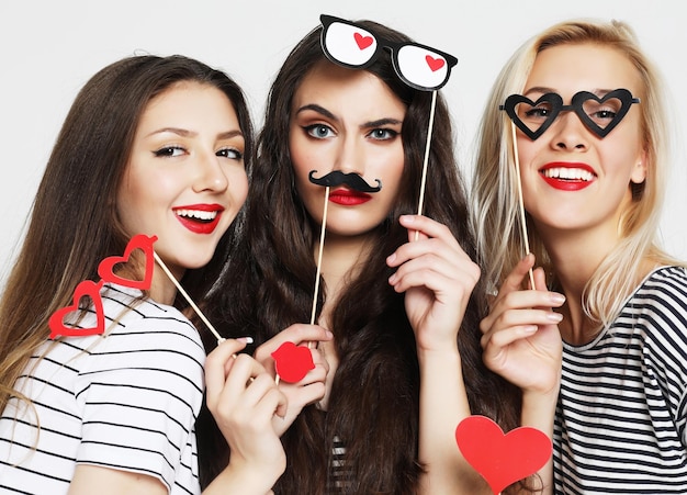 Three young women holding paper party sticks