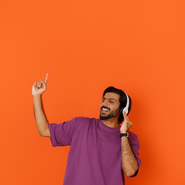 Thrilled young eastern guy enjoying his newest wireless headphones