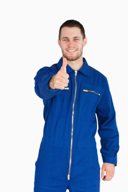 Thumb up given by smiling young mechanic in boiler suit