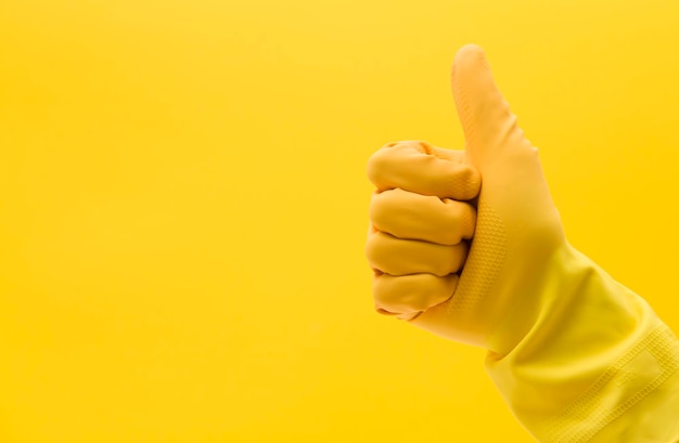 Thumbs up hand gesture made by a hand in a yellow rubber cleaning glove