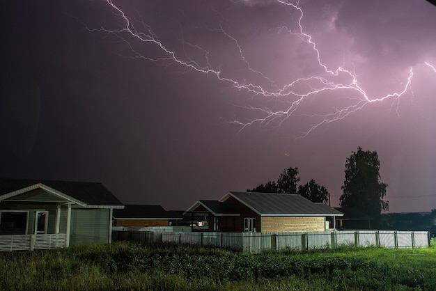 Thunderbolt over the house in the village and dark stormy sky on the background