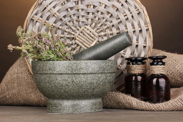 Thyme herb and mortar on wooden table on brown background