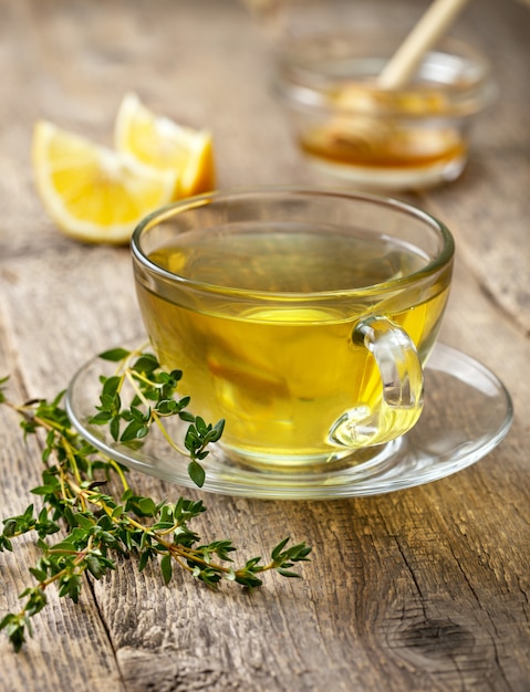 Thyme tea in glass cup on wooden table