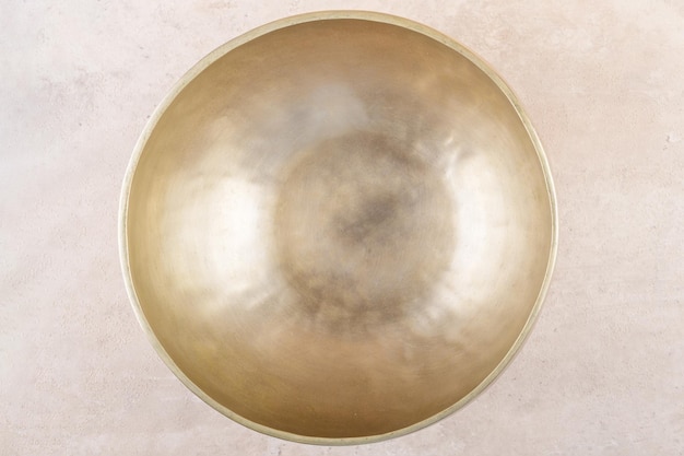 Tibetan singing bowl used during mantra meditations on beige stone background top view flat lay close up