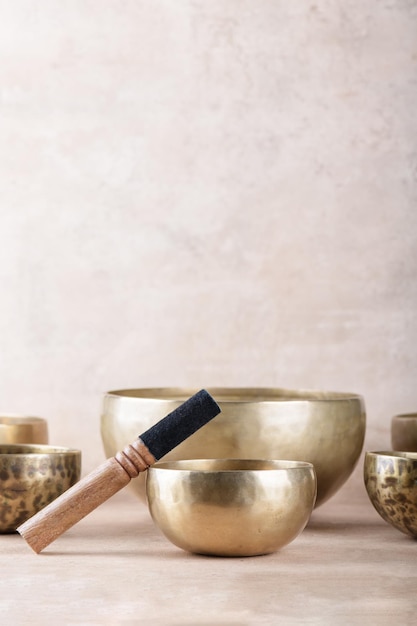 Tibetan singing bowls with sticks used during mantra meditations on beige stone background copy space