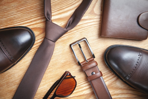 Tie, belt, wallet, shoes, sunglasses on the wooden background.