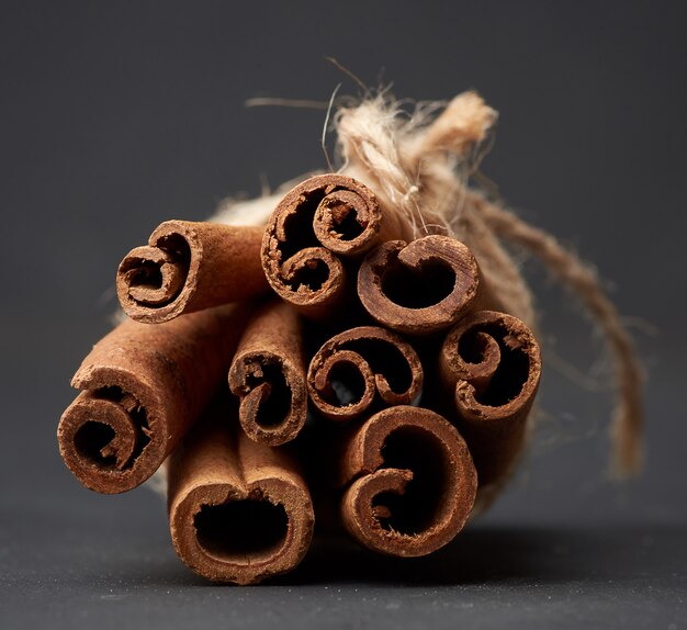 Photo tied bunch of brown cinnamon sticks on a dark background