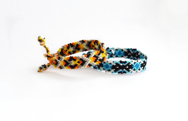 Tied DIY friendship bracelet with unusual braiding pattern on white background