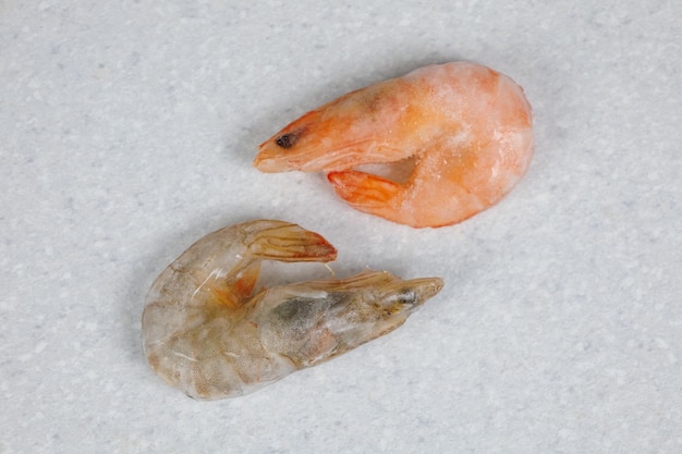 Tiger and king prawns lie on a light table Frozen products in ice glaze