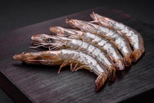 Tiger prawn or langoustine raw with spices and salt on a wooden cutting board