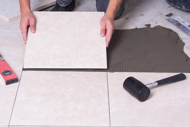 Tiler installing ceramic tiles on a floor