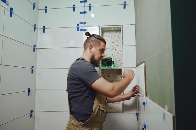 Tiler laying installing ceramic tiles on the wall in the bathroom