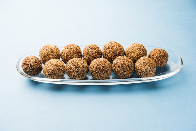 Tilgul Laddu or Til Gul balls for makar sankranti, it's a healthy food made using sesame, crushed peanuts and jaggery. served in a bowl. selective focus showing details.