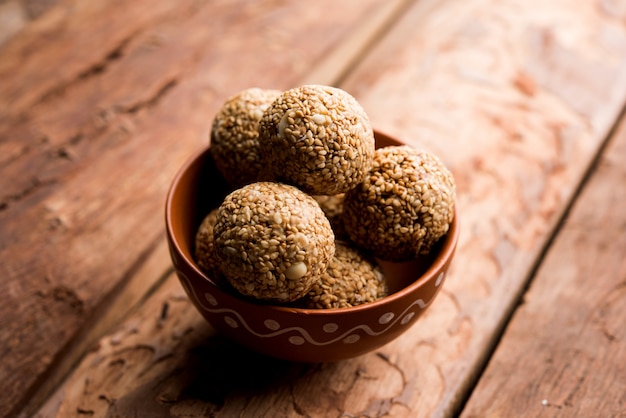 Tilgul Laddu or Til Gul balls for makar sankranti, it's a healthy food made using sesame, crushed peanuts and jaggery. served in a bowl. selective focus showing details.