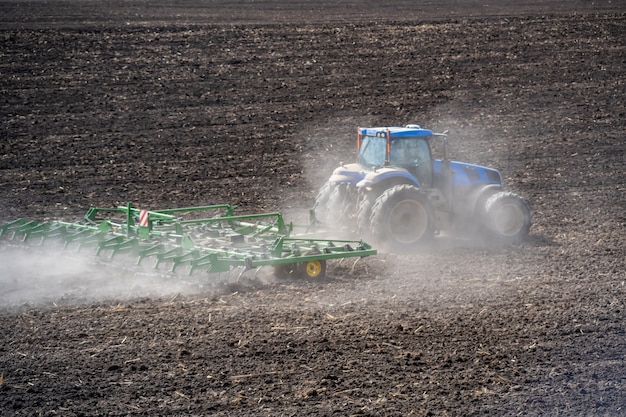 Tillage in the field with a tractor with a trailed machine.