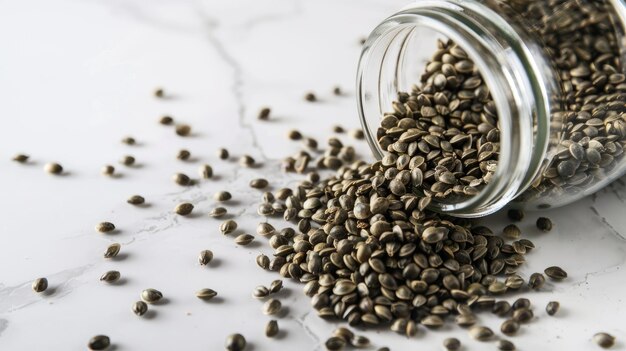 Tilted jar spilling hemp seeds on marble surface