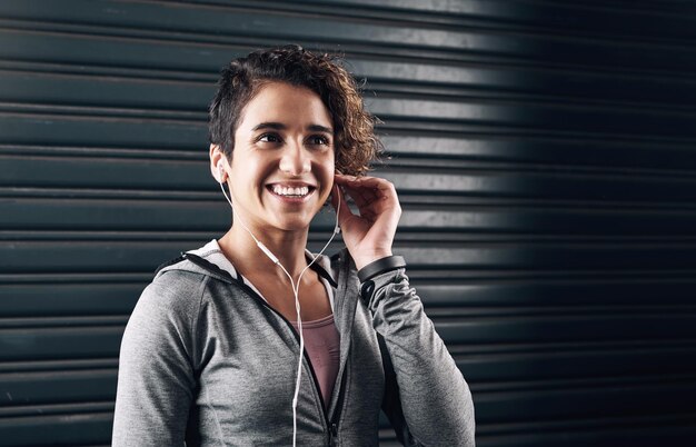 Time to blow off some steam Shot of a young woman choosing the perfect song for her run outside against a black background