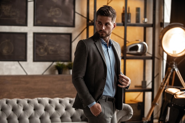 Time to go. Handsome young man looking away and keeping hands in pockets while walking through the room