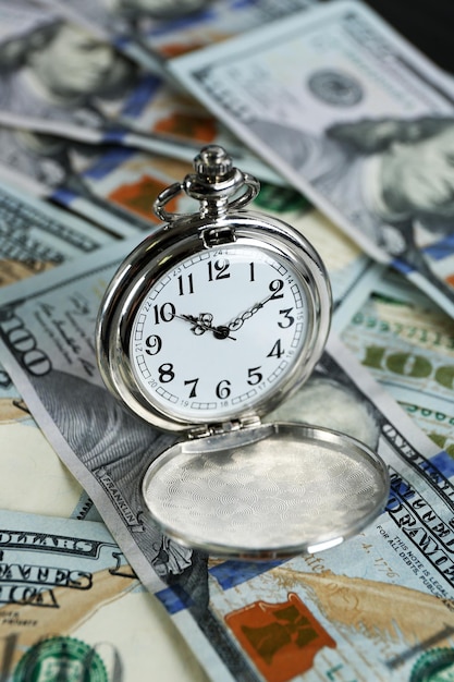 Photo time is money concept with pocket watch and dollars bills closeup