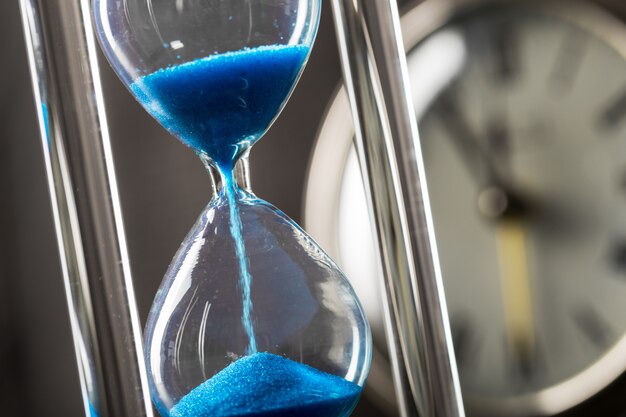 Time is passing. Blue hourglass close up