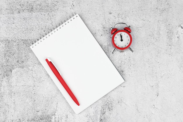 Time management concept. To-do list: red alarm clock, pencil and notebook